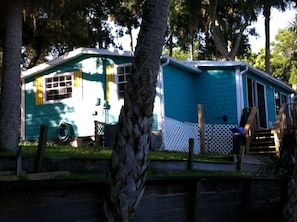 A mobile home with a fenced yard, a wooden deck, and a staircase leading to the entrance.