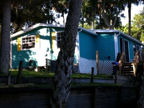 A mobile home with a fenced yard, a wooden deck, and a staircase leading to the entrance.