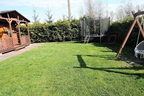 A wooden playhouse, a trampoline, and a swing set in a backyard. - Holiday Home in Kolczewo Near Baltic Sea (gmina Wolin)