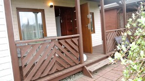 Une véranda en bois avec une balustrade, une porte et une fenêtre.
