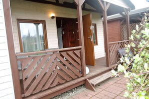 A wooden porch with a railing, a door, and a window. - Holiday Home in Kolczewo Near Baltic Sea (gmina Wolin)