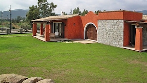 Een modern huis met een gevel van natuursteen, een overdekt terras en een verzorgd gazon.