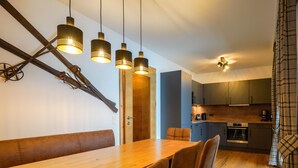 Une cuisine moderne avec des meubles en bois, un four encastré et des luminaires suspendus.