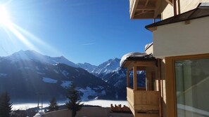 A mountain view with a wooden balcony and a glass door. - Kitzbuhel Alpine Lodge With Sauna (Mittersill)