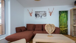 Un salon moderne avec un canapé d’angle, une table basse et une grande fenêtre.