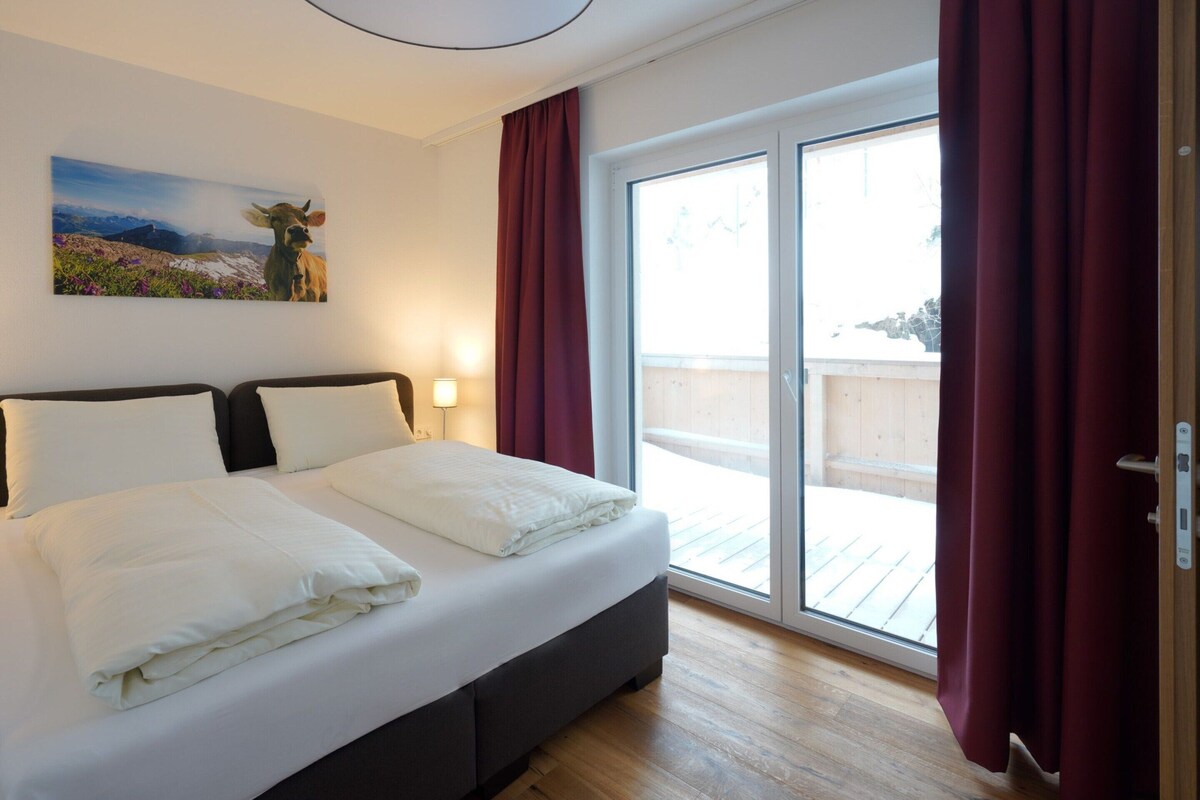 A bedroom with a bed, a painting, a sliding glass door, and a view of the outdoors.
