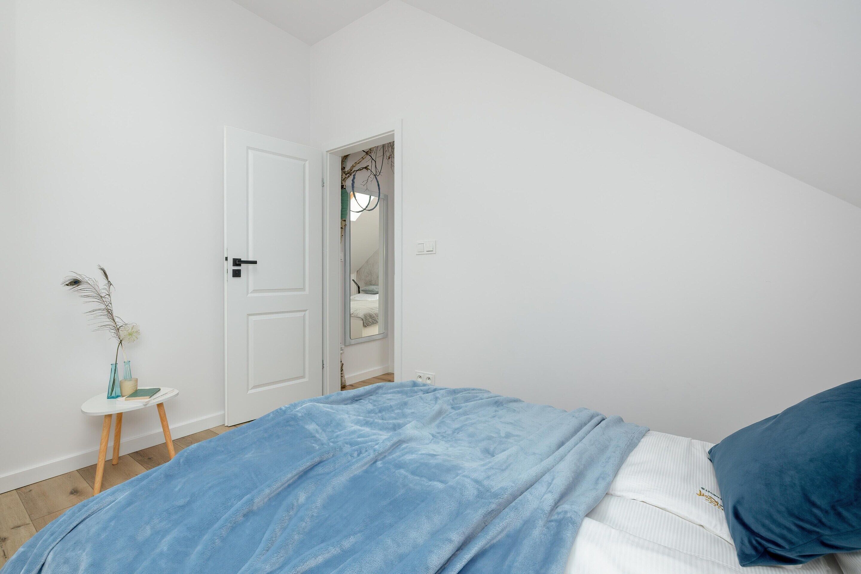 Une chambre à coucher avec un lit, une petite table de chevet, une porte et un miroir.