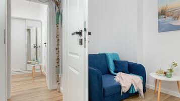 A room with a blue sofa, a small white table, and a painting on the wall.