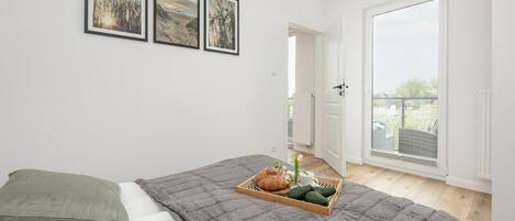A bedroom with a bed, a tray with food, and a view of the outside.