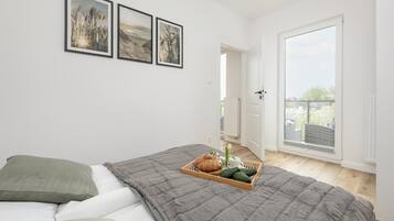 Ein Schlafzimmer mit einem Bett, einer grauen Steudecke, einem Tablett mit Speisen und Blick auf einen Balkon.