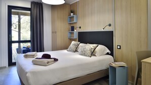 A modern bedroom with a large bed, a bedside table, a chair, and a window with curtains. - Group Stay Near Sea in Propriano (Belvedere-Campomoro)