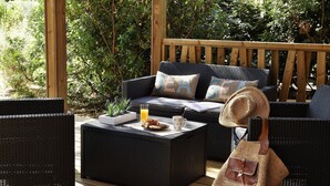 A covered outdoor seating area with wicker furniture, a wooden deck, and a view of greenery. - Group Stay Near Sea in Propriano (Belvedere-Campomoro)