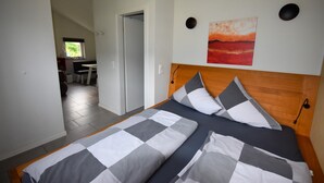 Ein Schlafzimmer mit karierter Bettdecke, einem Holzkopfteil und einem Bild an der Wand.