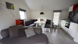 Ein stilvoller Wohnraum mit grauem Sofa, einem Esstisch und einer Küchenzeile.