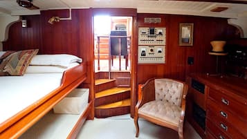 Una cabaña de madera con una cama, una silla, una escalera y un panel de control.