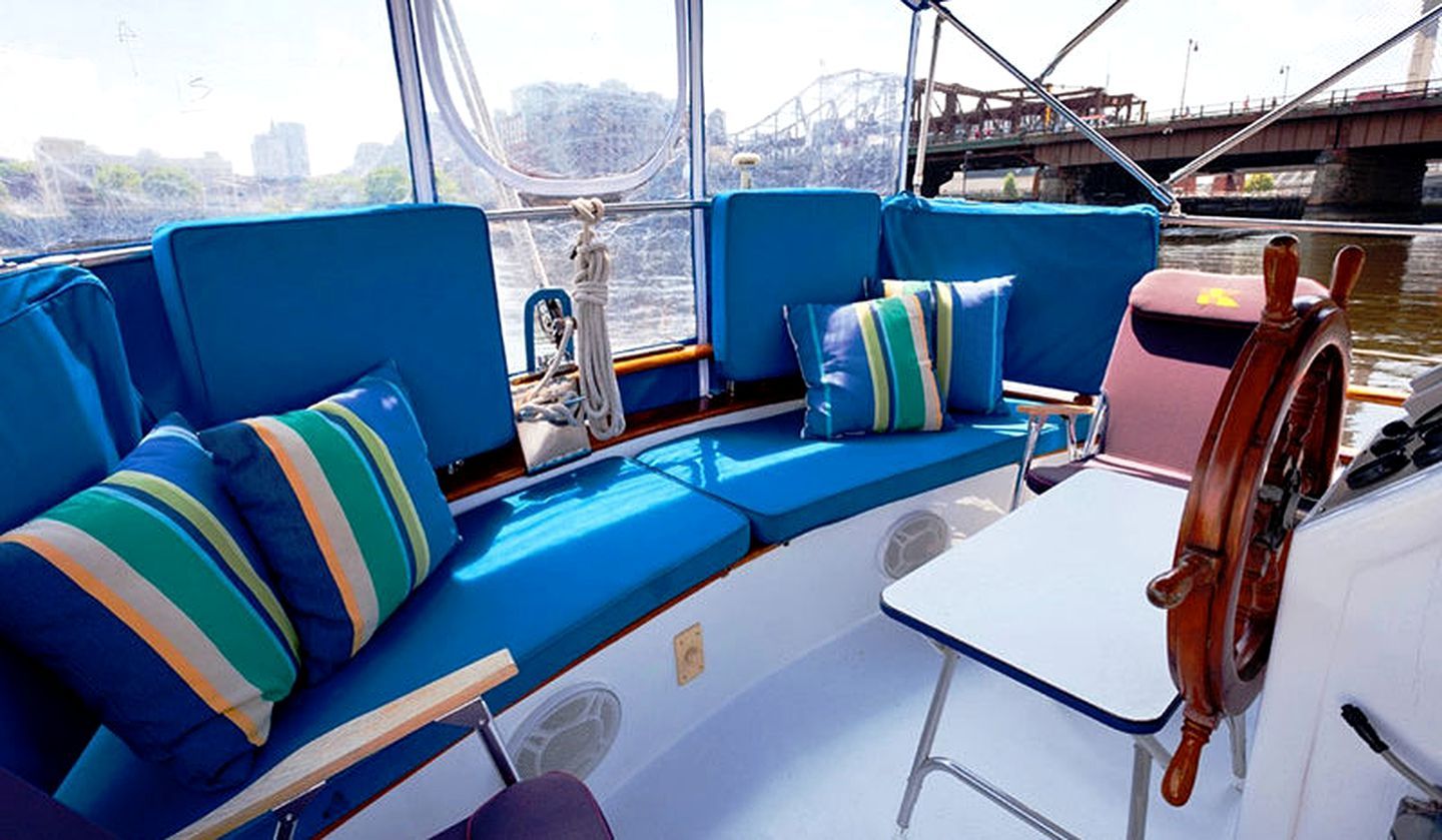 L’intérieur d’un bateau, avec un coin salon doté de sièges rembourrés bleus, une petite table et un volant.