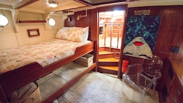 Una cabaña compacta con literas, una pequeña zona de estar y una puerta que da a un espacio exterior.