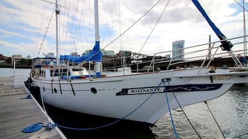 Un velero llamado 'ROZINANTE' atracado en un puerto deportivo, con un horizonte urbano al fondo.