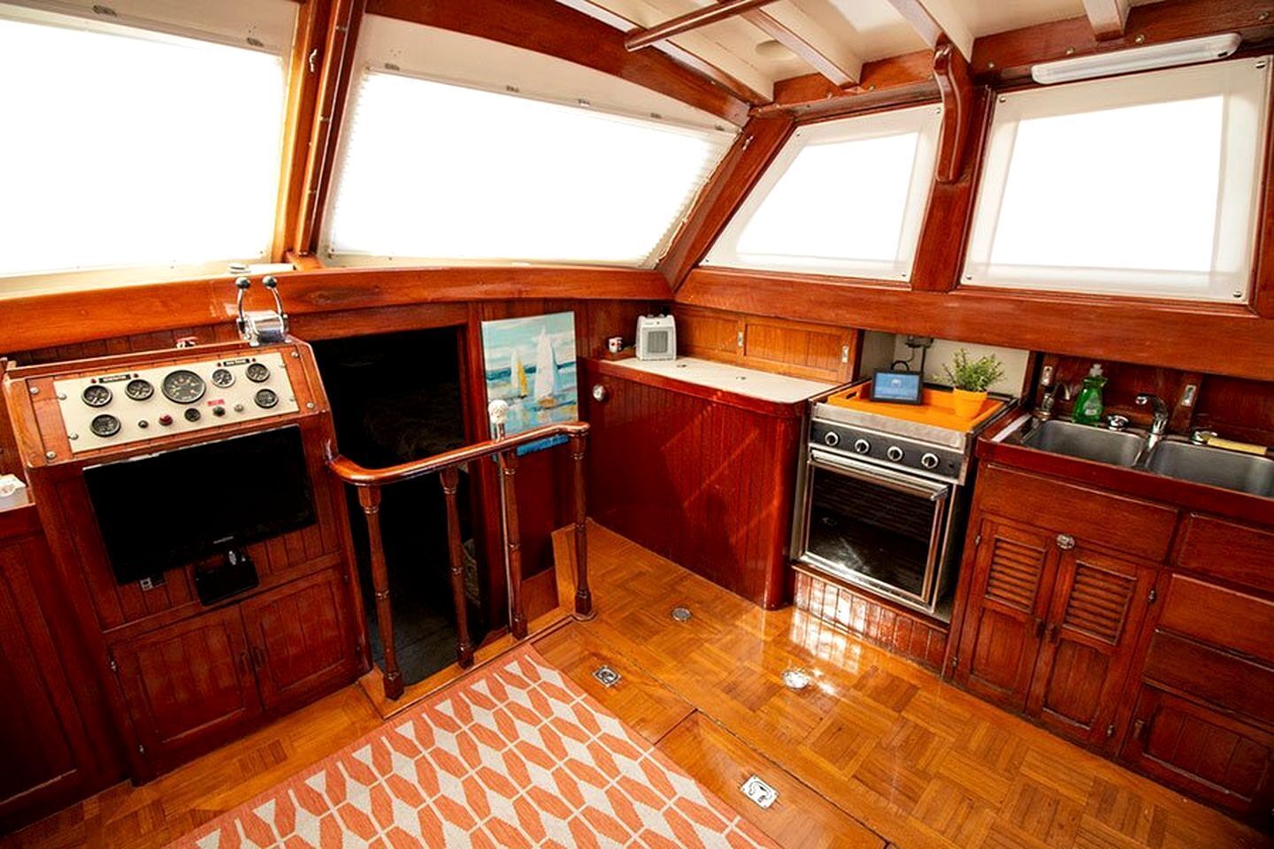 Una cocina pequeña e integrada con estufa, lavamanos y un refrigerador compacto.
