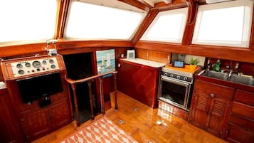 Una cocina pequeña e integrada con estufa, lavamanos y un refrigerador compacto.