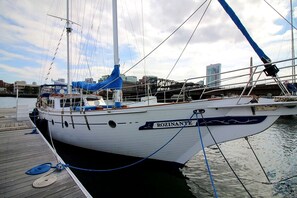 Un velero llamado 'ROZINANTE' atracado en un puerto deportivo, con un horizonte urbano al fondo.