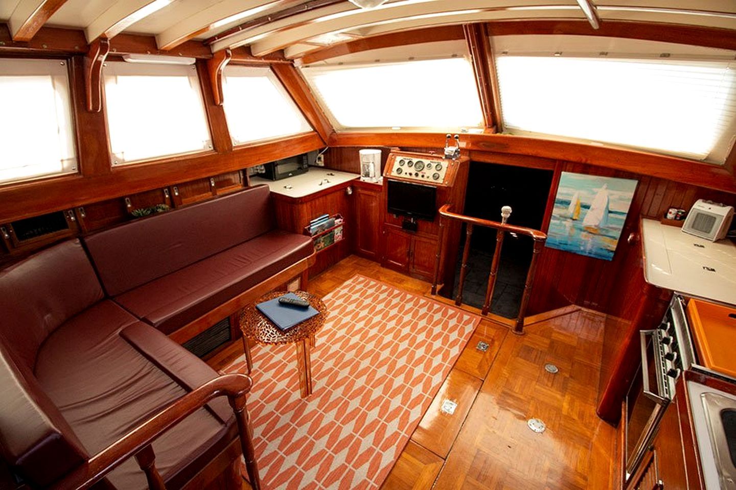 Un interior acogedor con un banco de madera, una mesita, un panel de control y una ventana.