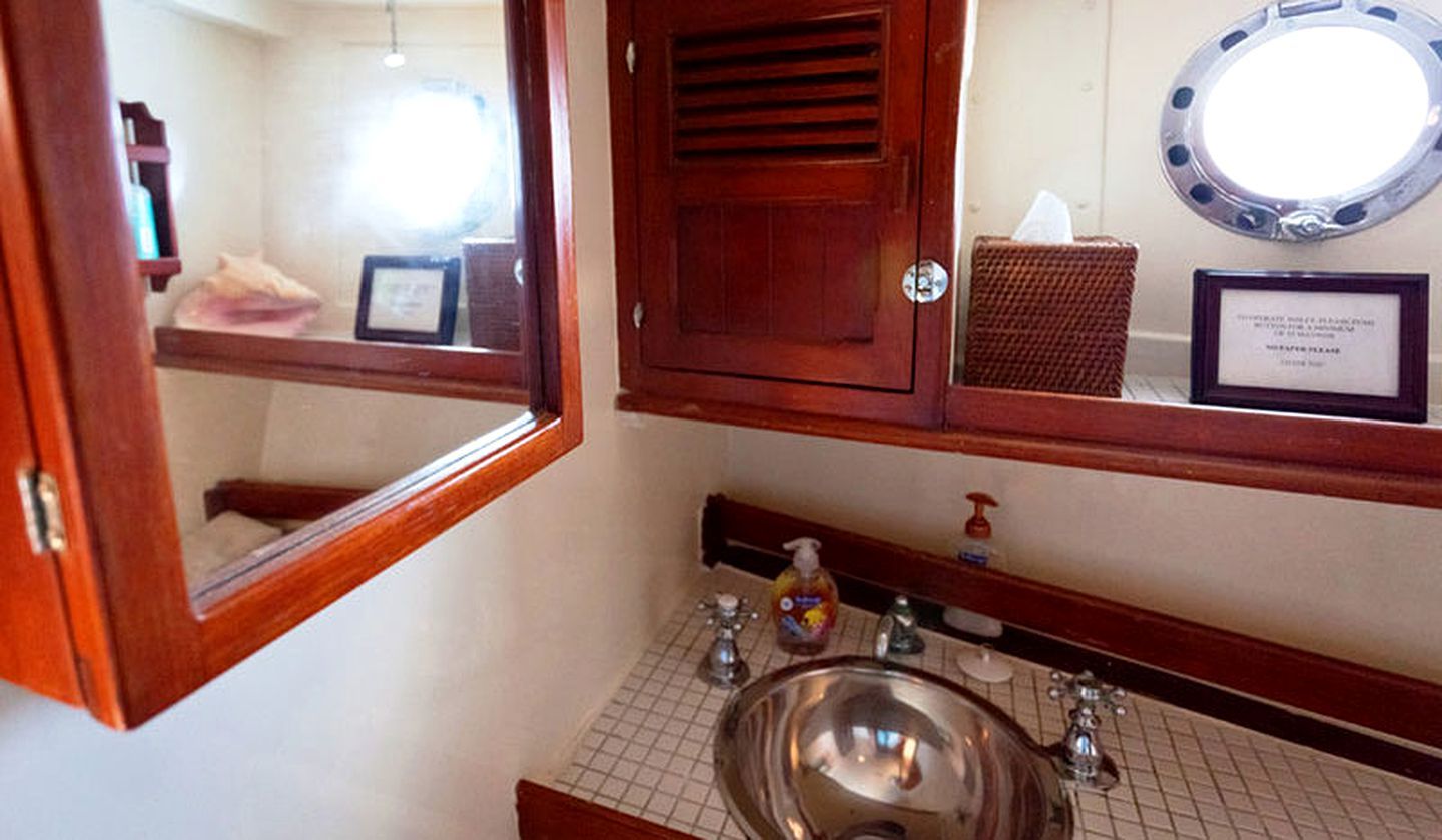 Un baño con tocador de madera, un lavamanos, un espejo y un certificado enmarcado en la pared.