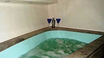 Una piscina rectangular con agua cristalina, dos grifos azules y suelo de baldosas.