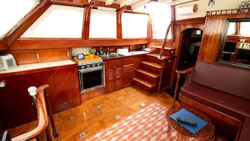 Una pequeña cocina tipo camarote con estufa, fregadero y armarios de madera.