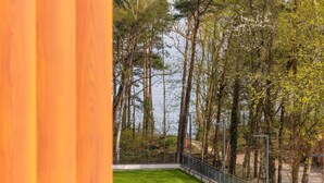 A view of a forested area with tall trees and a body of water in the background. - Holiday Studio Near the Beach, Pool, Sauna (Rewal)