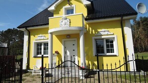 A two-story house with a yellow facade, a black roof, and a white door. - Holidayhome in Nowe Warpno for 10 Persons (Nowe Warpno)