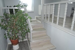 A staircase with white balusters and a potted plant at the base. - House in Nowogard by Lake Nowogardzkie (Nowogard)
