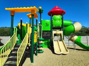 Ein Spielplatz mit Rutsche, Klettergerüsten und einem grün-gelben Spielbereich.