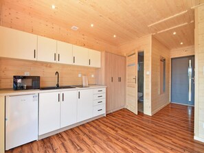A modern kitchen with wooden cabinets, a microwave, and a sink. - Comfortable, Single-story Holiday Homes (gmina Sianów)