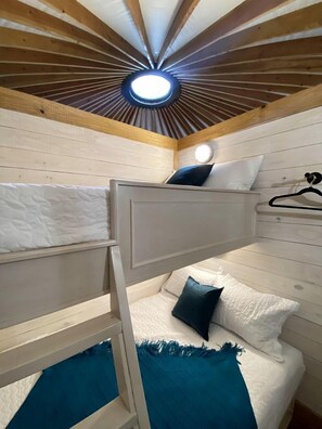 A bunk bed room with a skylight ceiling and a hanging light fixture.