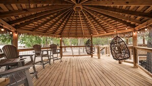 A wooden gazebo with a thatched roof, seating area, and hanging chairs. - A Yurt for Everyone: Family and Friends Getaway in Bandera, TX (Bandera)