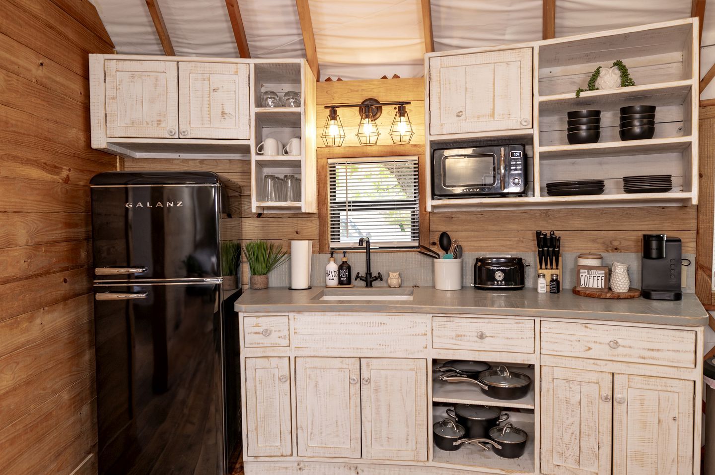 A compact kitchen with a Galanz refrigerator, a microwave, and wooden cabinets.