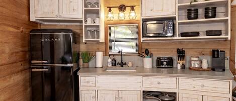 A compact kitchen with a Galanz refrigerator, a microwave, and wooden cabinets.