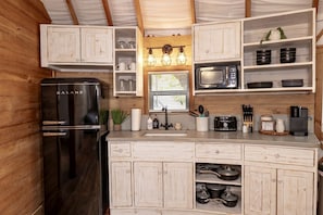 A compact kitchen with a Galanz refrigerator, a microwave, and wooden cabinets. - A Yurt for Everyone: Family and Friends Getaway in Bandera, TX (Bandera)