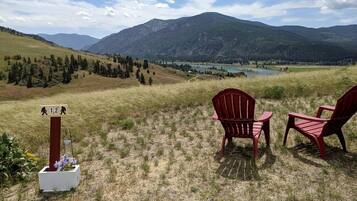 A scenic view with chairs and a signpost in a grassy field.
