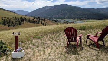 A scenic view with chairs and a signpost in a grassy field.