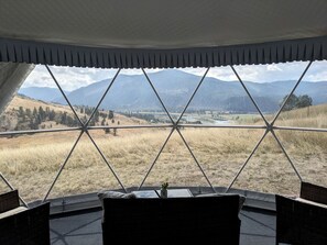 A room with a view of a mountainous landscape through a geometric window design.