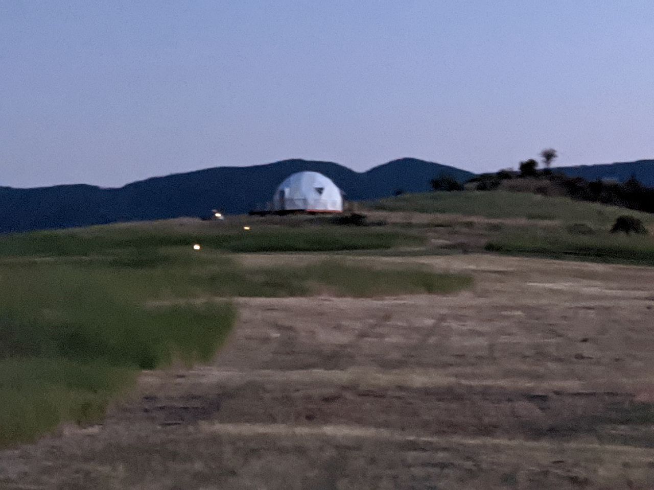 A dome-shaped building on a hill with a clear sky.