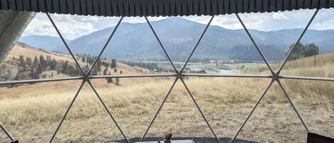 A room with a view of a mountainous landscape through a geometric window design.