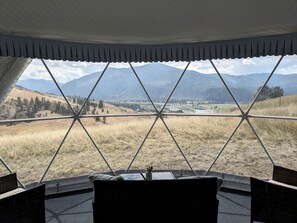 A room with a view of a mountainous landscape through a geometric window design.
