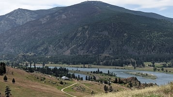 A mountainous landscape with a river, a small settlement, and a clear sky.
