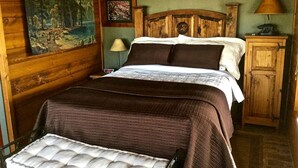 A wooden bed with a headboard, a nightstand with a lamp, a painting on the wall, and a wooden cabinet. - Quiet Cottage Rental for Two in Horse Country near Yosemite National Park Gateway, California (Catheys Valley)