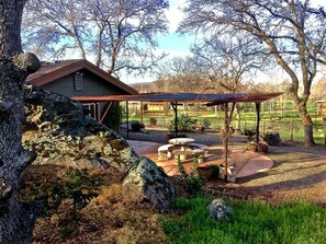 A rustic house with a patio area featuring a pergola, outdoor seating, and a stone fountain.
