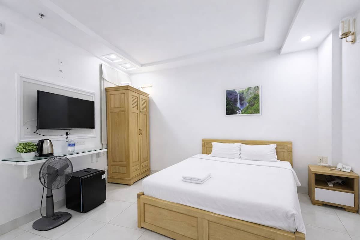 A bedroom with a bed, a TV, a wardrobe, a bedside table, and a picture on the wall.