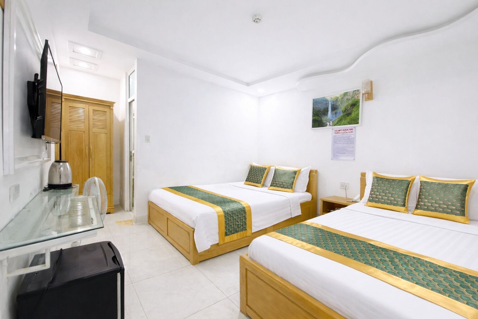 A hotel room with two beds, a desk, a TV, and a picture on the wall.